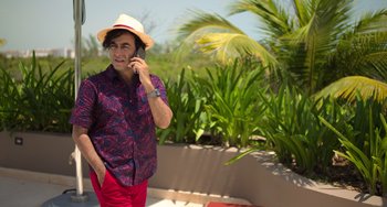 Movie still from “40 Years Young” (2022), directed by Pietro Loprieno – A man wearing a hat talking on a cell phone; Medium shot, Low angle