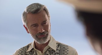 Movie still from “40 Years Young” (2022), directed by Pietro Loprieno – An older man with a gray beard is looking at the camera; Close Up shot, Over the shoulder angle
