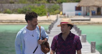 Movie still from “40 Years Young” (2022), directed by Pietro Loprieno – Two men are talking to each other while holding a purse; Medium shot, Over the shoulder angle
