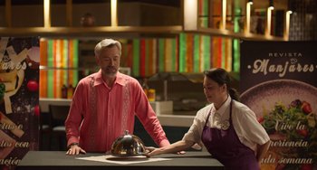 Movie still from “40 Years Young” (2022), directed by Pietro Loprieno – A man and a woman standing at a counter; Medium shot, High angle