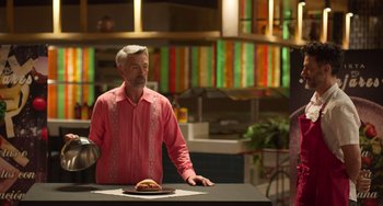 Movie still from “40 Years Young” (2022), directed by Pietro Loprieno – An older man standing in front of a plate of food; Medium shot, Low angle