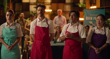 Movie still from “40 Years Young” (2022), directed by Pietro Loprieno – A couple of men standing next to each other in aprons; Medium shot, Over the shoulder angle