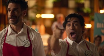 Movie still from “40 Years Young” (2022), directed by Pietro Loprieno – A man in a white shirt and a red apron; Medium shot, Over the shoulder angle