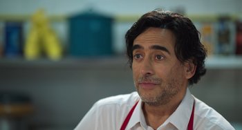 Movie still from “40 Years Young” (2022), directed by Pietro Loprieno – A person wearing an apron; Close Up shot, Over the shoulder angle