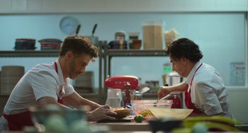 Movie still from “40 Years Young” (2022), directed by Pietro Loprieno – Two men are preparing food in a commercial kitchen; Medium shot, Low angle