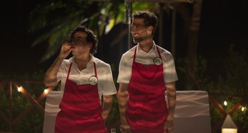 Movie still from “40 Years Young” (2022), directed by Pietro Loprieno – Two men in red aprons standing next to each other; Medium shot, Over the shoulder angle