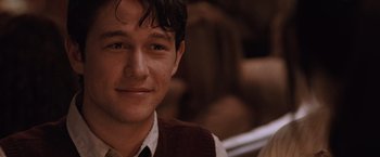 Movie still from “500 Days of Summer” (2009), directed by Marc Webb – A young man in a brown vest and a white collared shirt is smiling; Close Up shot, Over the shoulder angle