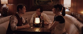 Movie still from “500 Days of Summer” (2009), directed by Marc Webb – A group of people sitting at a table with bottles of beer; Medium shot, Over the shoulder angle