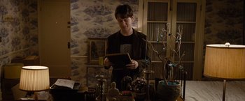 Movie still from “500 Days of Summer” (2009), directed by Marc Webb – A man standing in front of a table holding a book; Medium shot, Over the shoulder angle