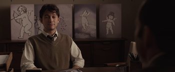 Movie still from “500 Days of Summer” (2009), directed by Marc Webb – A man sitting in front of three paintings; Medium shot, Over the shoulder angle