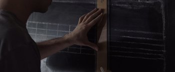 Movie still from “500 Days of Summer” (2009), directed by Marc Webb – A hand is holding a piece of wood and writing on it with a marker; Extreme Close Up shot, Overhead angle