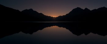 Movie still from “65” (2023), directed by Bryan Woods – The sun is setting over a mountain range; Extreme Wide shot, High angle