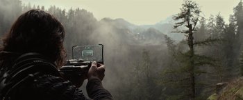 Movie still from “65” (2023), directed by Bryan Woods – A person taking a picture of a foggy mountain; Wide shot, High angle