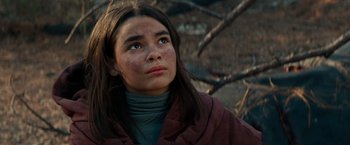 Movie still from “65” (2023), directed by Bryan Woods – A young woman looking to her left while standing in front of a tree; Close Up shot, Low angle