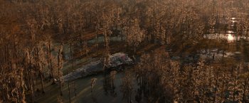 Movie still from “65” (2023), directed by Bryan Woods – An aerial view of trees and a body of water; Extreme Wide shot, High angle