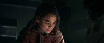 Movie still from “65” (2023), directed by Bryan Woods – A young girl is looking down at her face; Close Up shot, Over the shoulder angle