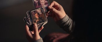 Movie still from “65” (2023), directed by Bryan Woods – A person holding a stack of photos in their hands; Extreme Close Up shot, Overhead angle