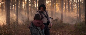 Movie still from “65” (2023), directed by Bryan Woods – A man and a young girl walking through the woods; Medium shot, Over the shoulder angle