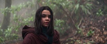 Movie still from “65” (2023), directed by Bryan Woods – A woman with long black hair wearing a red jacket; Close Up shot, Low angle