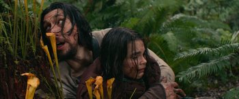 Movie still from “65” (2023), directed by Bryan Woods – A man and a woman sitting on the ground in the woods; Close Up shot, Low angle