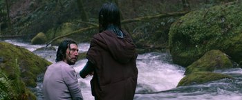 Movie still from “65” (2023), directed by Bryan Woods – A man and a woman standing next to each other in the water; Medium shot, Over the shoulder angle