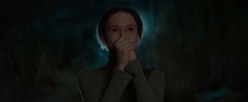 Movie still from “65” (2023), directed by Bryan Woods – A young woman covers her face with her hands; Close Up shot, Low angle