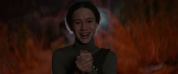 Movie still from “65” (2023), directed by Bryan Woods – A young woman smiling and clapping her hands; Close Up shot, Low angle