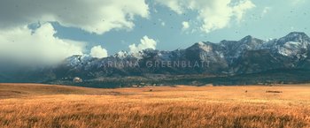 Movie still from “65” (2023), directed by Bryan Woods – A large open field with mountains in the background; Extreme Wide shot, Over the shoulder angle