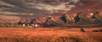 Movie still from “65” (2023), directed by Bryan Woods – An image of an open field with mountains in the background; Extreme Wide shot, High angle