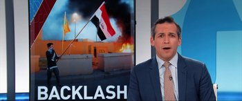 Movie still from “752 Is Not a Number” (2022), directed by Babak Payami – A man in a suit and tie standing in front of a television screen; Close Up shot, Over the shoulder angle