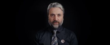 Movie still from “752 Is Not a Number” (2022), directed by Babak Payami – A man with a gray beard wearing a tie; Close Up shot, High angle