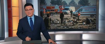 Movie still from “752 Is Not a Number” (2022), directed by Babak Payami – A man standing in front of a television; Medium shot, Low angle