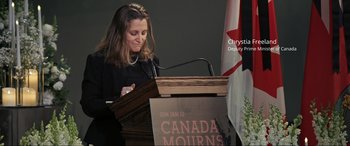 Movie still from “752 Is Not a Number” (2022), directed by Babak Payami – A woman standing at a podium with a microphone; Medium shot, Low angle