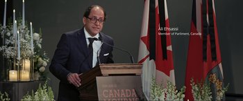 Movie still from “752 Is Not a Number” (2022), directed by Babak Payami – A man standing at a podium with a microphone; Medium shot, Low angle