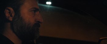 Movie still from “752 Is Not a Number” (2022), directed by Babak Payami – A man with a long beard is looking into the distance; Close Up shot, Over the shoulder angle