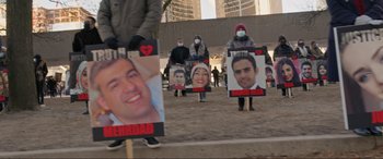 Movie still from “752 Is Not a Number” (2022), directed by Babak Payami – A group of people are holding signs with faces of people; Medium shot, High angle