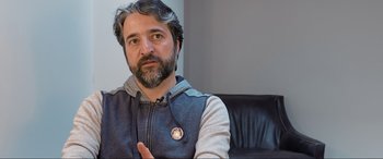 Movie still from “752 Is Not a Number” (2022), directed by Babak Payami – A man with long hair and a beard wearing a jacket; Close Up shot, Over the shoulder angle