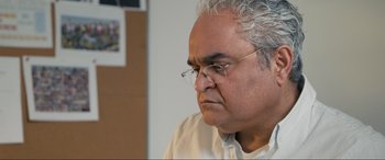 Movie still from “752 Is Not a Number” (2022), directed by Babak Payami – An older man wearing glasses and a white shirt; Close Up shot, Over the shoulder angle