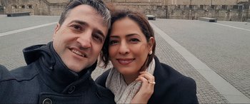 Movie still from “752 Is Not a Number” (2022), directed by Babak Payami – A man and a woman smile for a picture; Close Up shot, Overhead angle