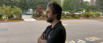 Movie still from “752 Is Not a Number” (2022), directed by Babak Payami – A man standing on the side of the road with his arms crossed; Medium shot, Over the shoulder angle