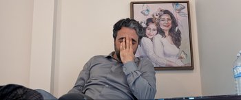 Movie still from “752 Is Not a Number” (2022), directed by Babak Payami – A man sitting in front of a picture of a woman; Close Up shot, Over the shoulder angle