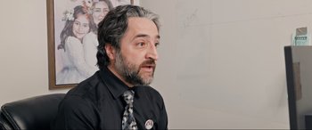 Movie still from “752 Is Not a Number” (2022), directed by Babak Payami – A man in a black shirt and a black tie; Close Up shot, Over the shoulder angle