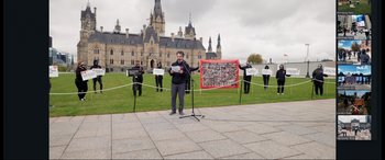 Movie still from “752 Is Not a Number” (2022), directed by Babak Payami – A man standing in front of a microphone on a grass field; Extreme Wide shot, High angle