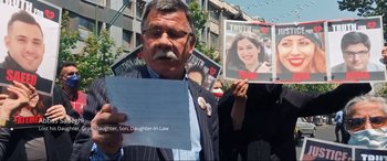 Movie still from “752 Is Not a Number” (2022), directed by Babak Payami – A man holding up a sign with a picture of a woman; Close Up shot, High angle