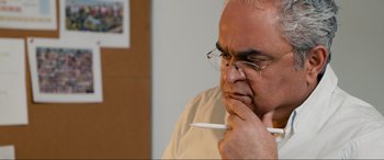 Movie still from “752 Is Not a Number” (2022), directed by Babak Payami – An older man with glasses is holding a pen; Close Up shot, High angle