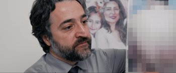 Movie still from “752 Is Not a Number” (2022), directed by Babak Payami – A person wearing a shirt and tie; Close Up shot, Over the shoulder angle