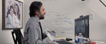 Movie still from “752 Is Not a Number” (2022), directed by Babak Payami – A man in a suit and tie holding a newspaper; Medium shot, Over the shoulder angle