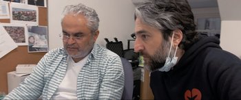 Movie still from “752 Is Not a Number” (2022), directed by Babak Payami – Two men sitting in front of a computer screen; Close Up shot, Over the shoulder angle