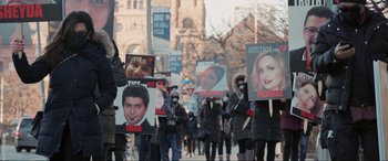 Movie still from “752 Is Not a Number” (2022), directed by Babak Payami – A group of people marching down a street holding signs; Medium shot, High angle