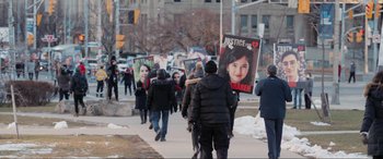 Movie still from “752 Is Not a Number” (2022), directed by Babak Payami – A group of people walking down a sidewalk holding signs; Medium shot, High angle